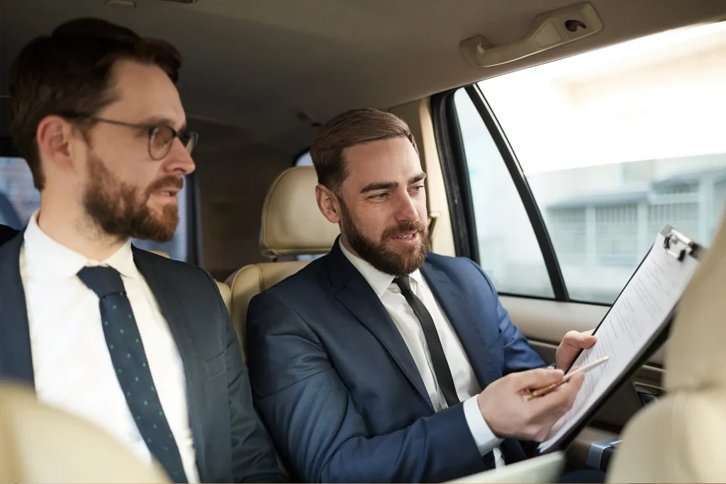 Two lawyers in the back of a car, going through a file