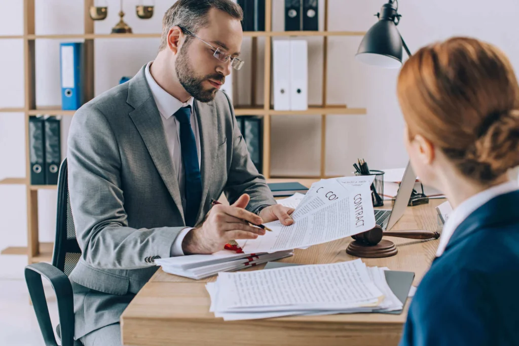 A lawyer goes through a contract with a client across a desk